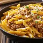 Flat lay of fresh ingredients for Cheesy Penne with Garlic Butter Ground Beef, including penne pasta, ground beef, minced garlic, and shredded cheese.